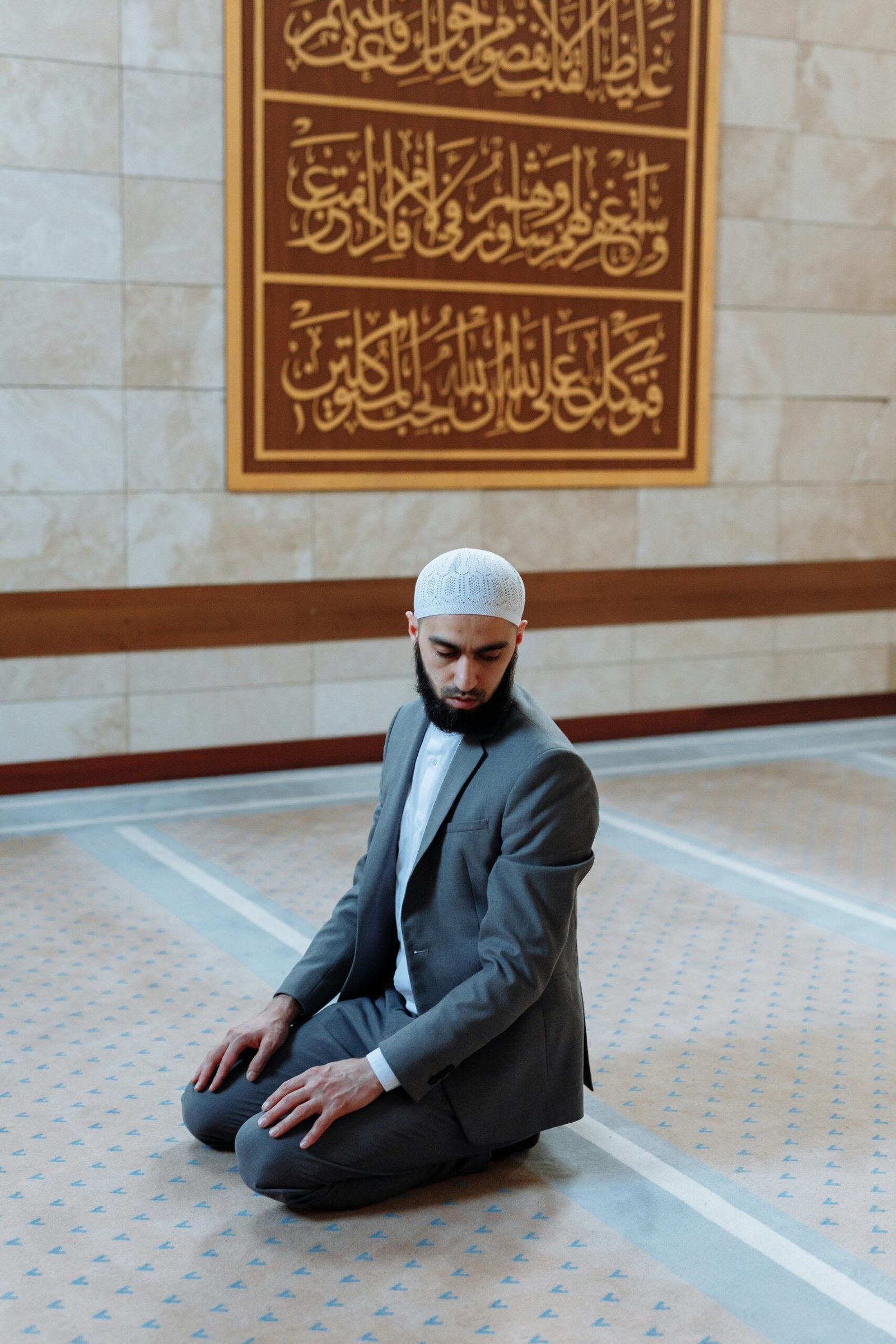 Muslim man kneeling in prayer inside a mosque, showcasing faith and devotion.