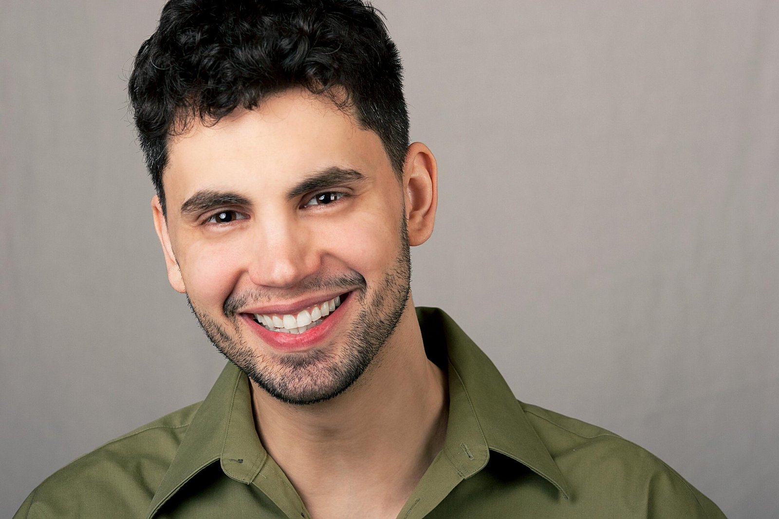 Smiling Hispanic man in green shirt portrait, Chicago setting.
