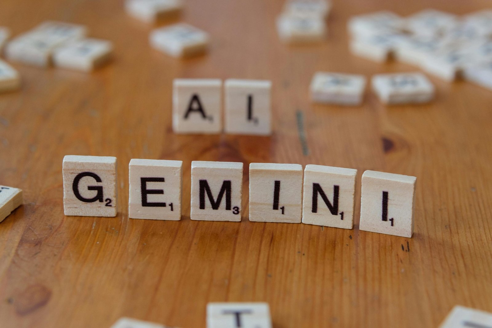 Scrabble tiles spell out the words 'Gemini' and 'AI' on a wooden surface, symbolizing technology and communication.