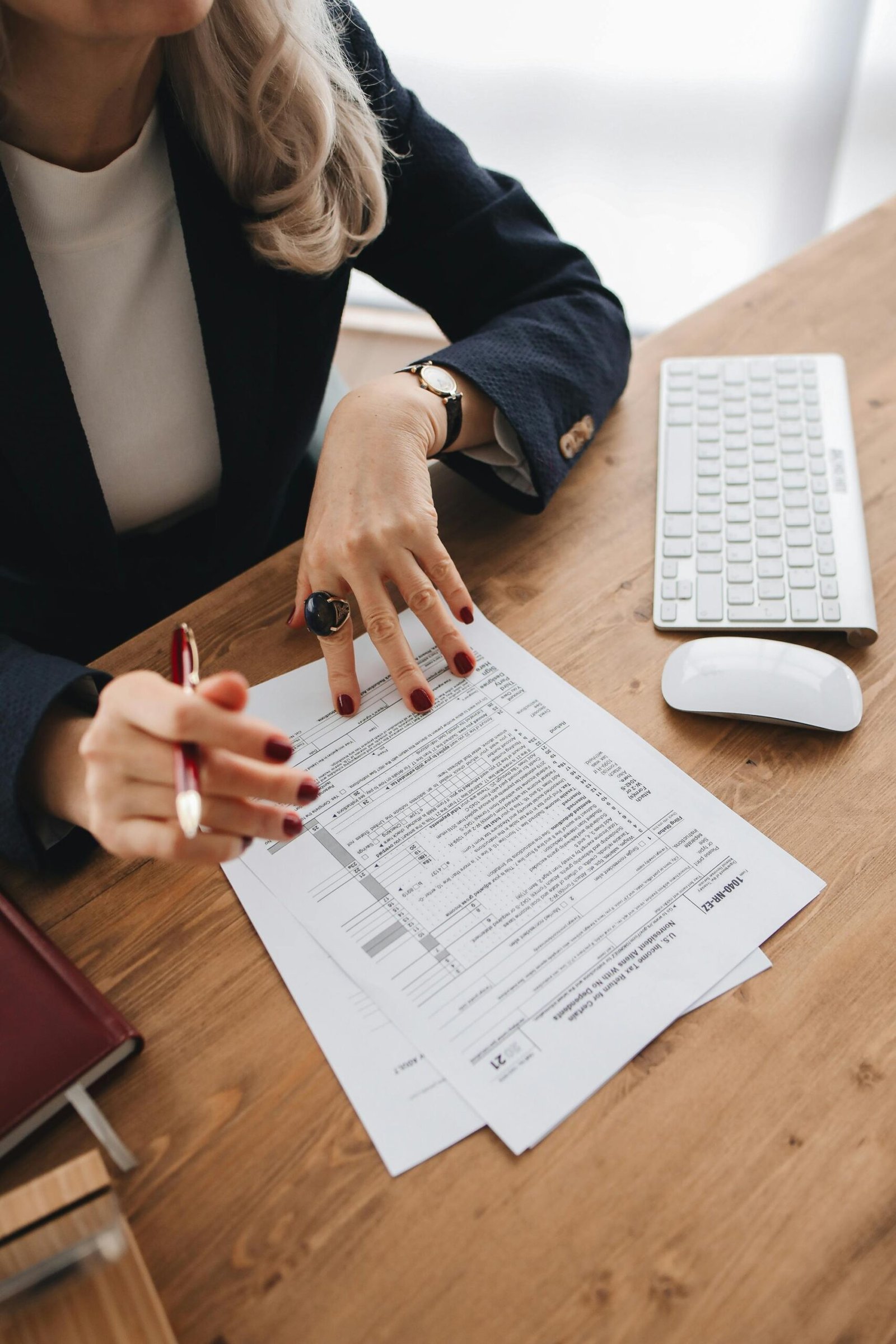Close-up of a professional examining tax documents on a wooden desk indoors.